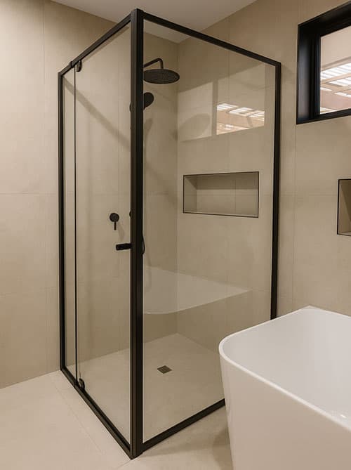 Semi-framed shower enclosure with black hardware in a tiled bathroom.
